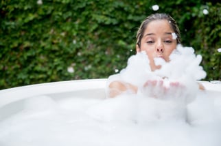 Happy woman taking a bubble bath and being playing with foam